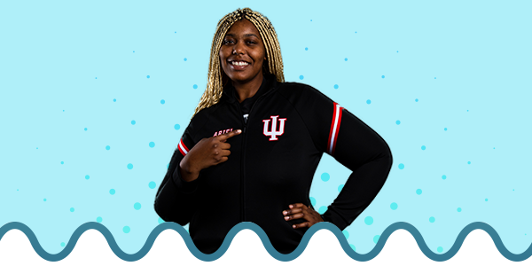 Female student pointing to the trident on her shirt, on top of a blue themed gradient background